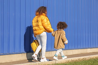 Mother and Child Walking Hand in Hand Against Blue Wall
