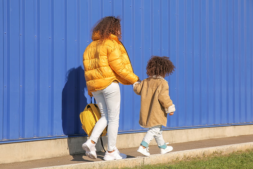 Mother and Child Walking Hand in Hand Against Blue Wall
