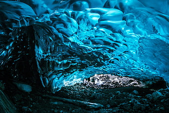 Glowing Blue Ice Cave Interior with Rocky Floor