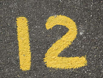 Yellow Number 12 Painted On Textured Asphalt Road Surface