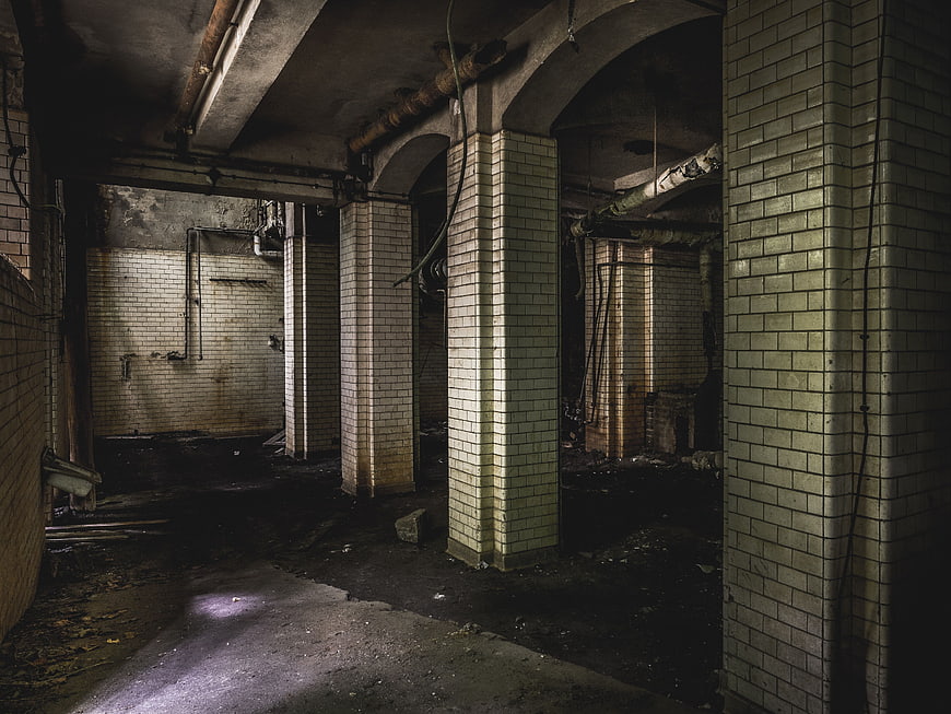 Abandoned industrial basement with tiled pillars and pipes