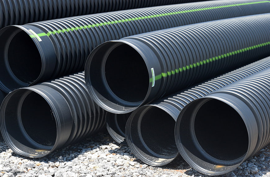 Stacked Black Corrugated Plastic Drainage Pipes With Green Stripes