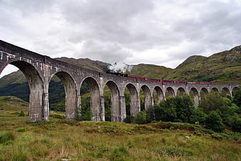 Steam train crossing Glenfinnan Viaduct in Scottish Highlands