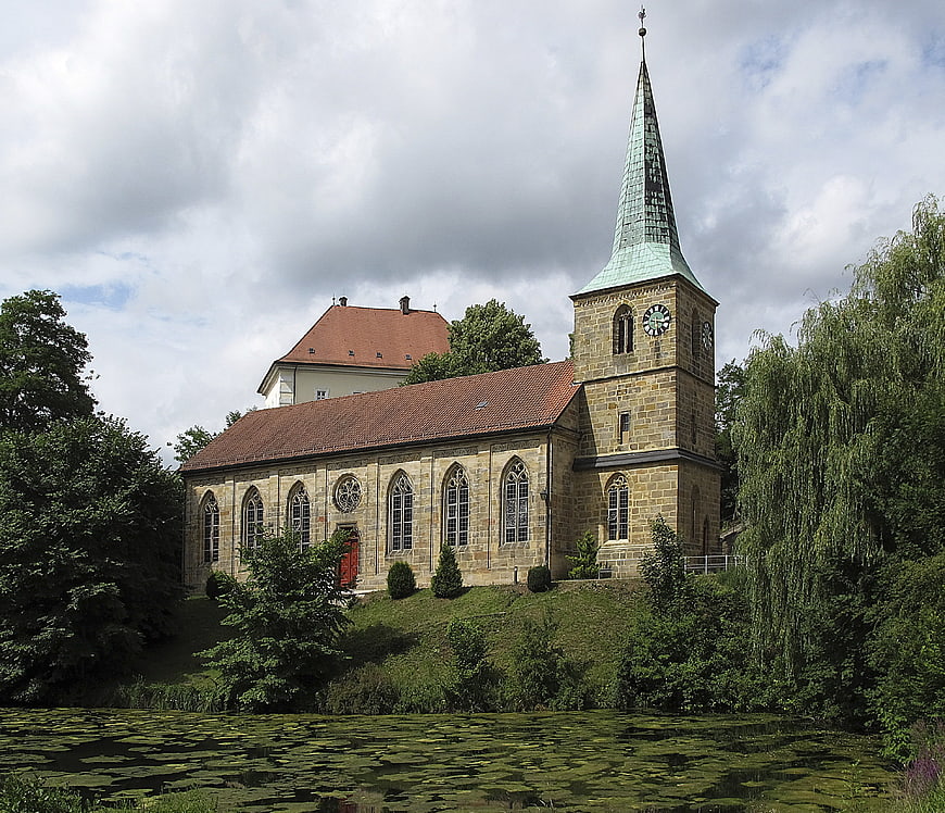 Historic stone church with spire by a lily pond