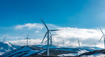 Wind Turbines On Snowy Hills Under Blue Sky