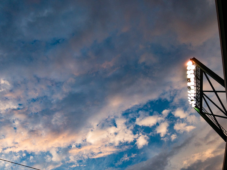 Stadium floodlights against dramatic cloudy sky at dusk