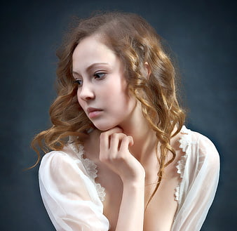Portrait of a woman with curly hair in a white lace top