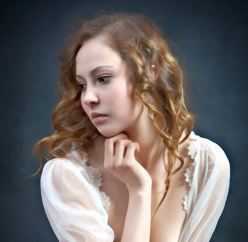 Portrait of a woman with curly hair in a white lace top