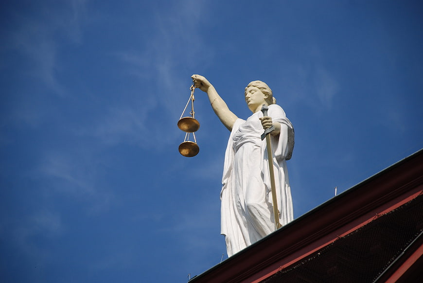 Lady Justice Statue with Scales and Sword Against Blue Sky