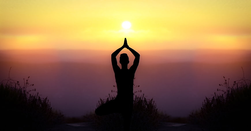 Silhouette of woman doing yoga at sunset