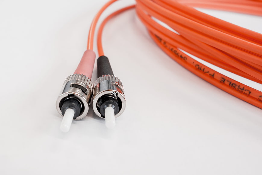 Close-up of orange fiber optic cable connectors on white background