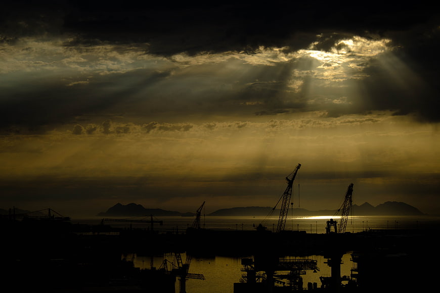 Dramatic Sun Rays Over Silhouetted Port Cranes at Sunset