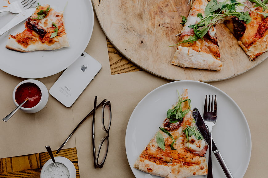 Top view of pizza slices on wooden board and plates