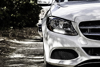Close-up of white luxury car headlight on dirt road