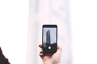 Hand holding smartphone taking photo of skyscraper
