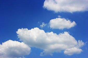 Fluffy white clouds against a vibrant blue summer sky