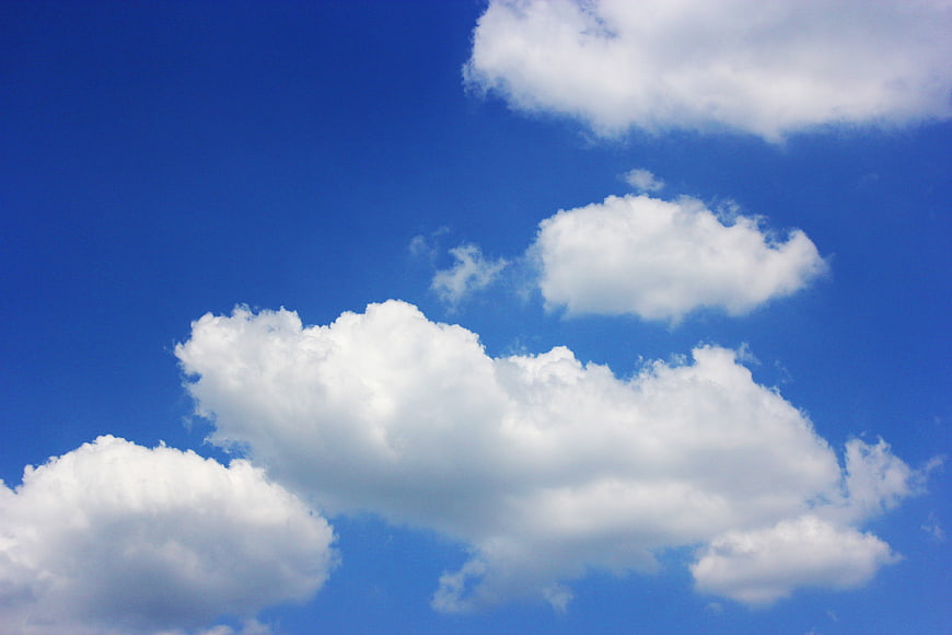 Fluffy white clouds against a vibrant blue summer sky