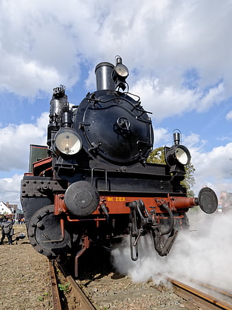 Vintage black steam locomotive emitting smoke on tracks