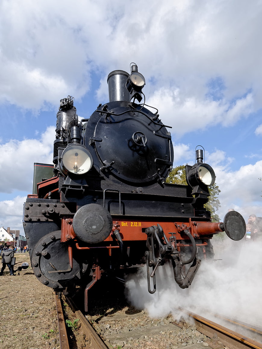 Vintage black steam locomotive emitting smoke on tracks