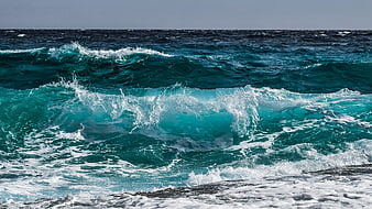 Powerful turquoise ocean waves crashing on rocky shore