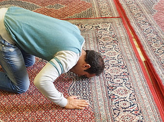 Muslim man praying on ornate Persian rug