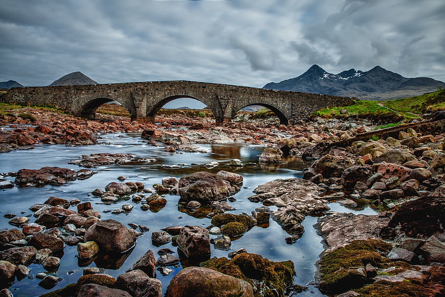 Dramatic stone bridge over rocky river in Scottish Highlands