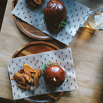 Top view of gourmet burgers with potato wedges on wooden table
