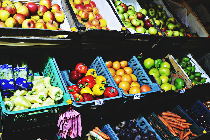 Fresh produce display with apples, peppers, and carrots in market crates