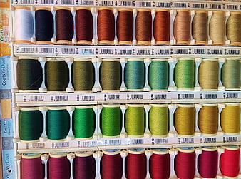 Colorful spools of sewing thread organized on a rack