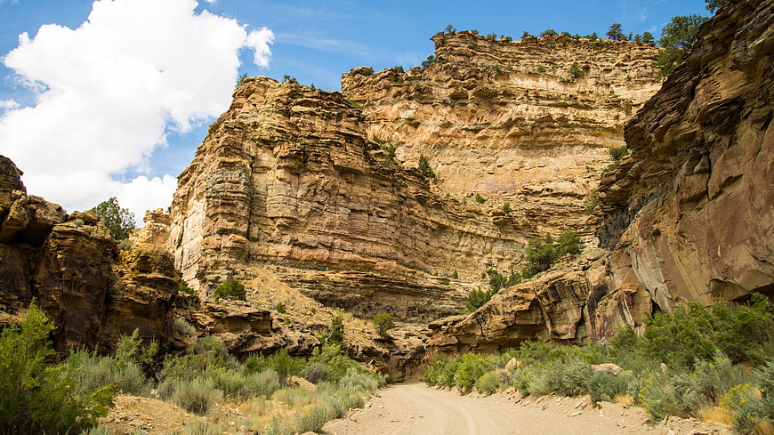 Dirt road winding through rugged canyon landscape with blue sky