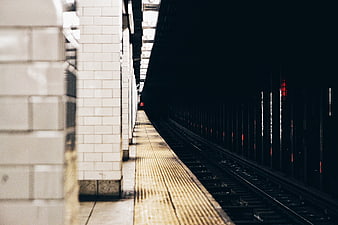 Empty subway platform with tracks leading into dark tunnel