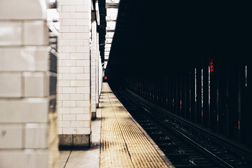 Empty subway platform with tracks leading into dark tunnel