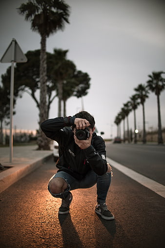 Photographer crouching on street with camera