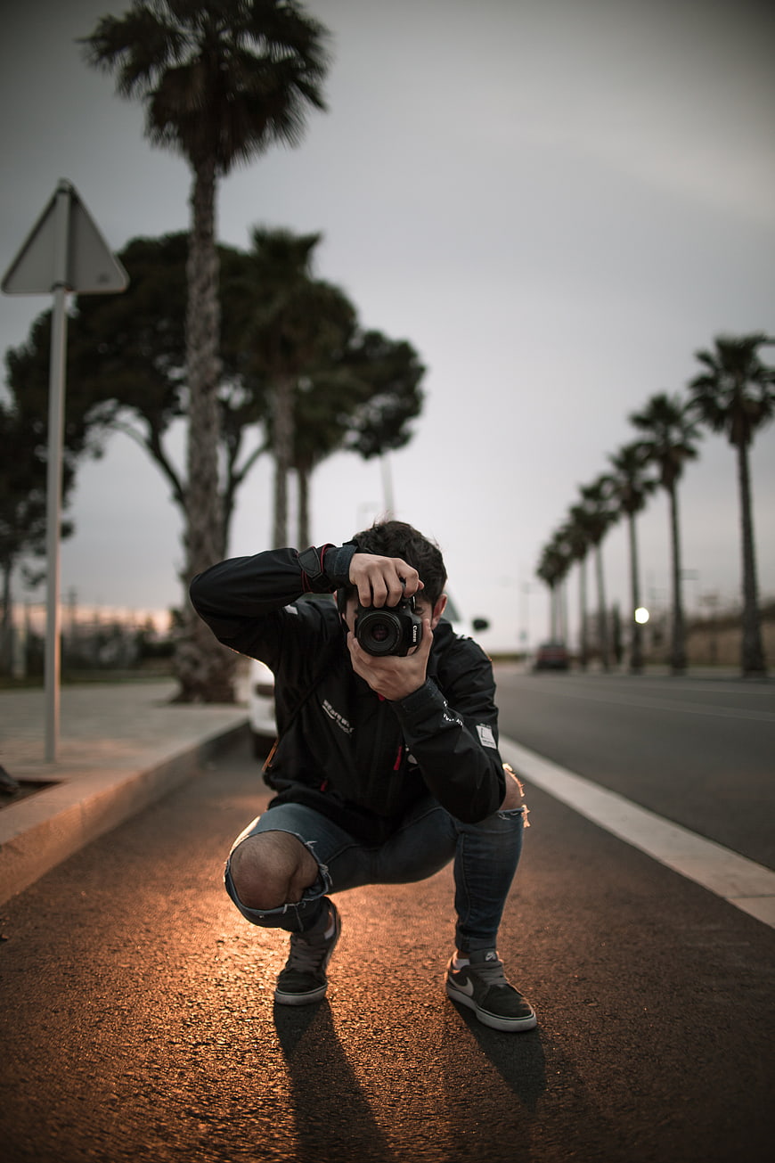 Photographer crouching on street with camera
