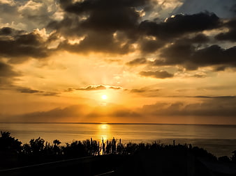 Dramatic Golden Sunset Over Ocean with Silhouetted Foreground