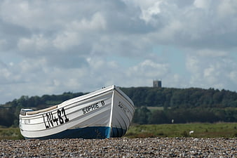 White and Blue Fishing Boat on Pebble Beach