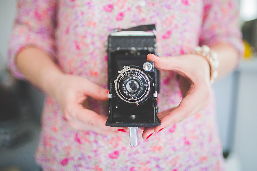Woman holding vintage folding camera