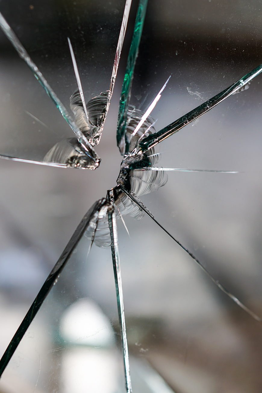 Close-up of shattered glass with radial cracks and central impact point