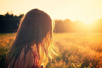 Woman with long hair in golden sunset field