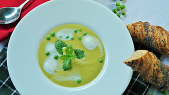 Overhead view of creamy green pea soup with bread