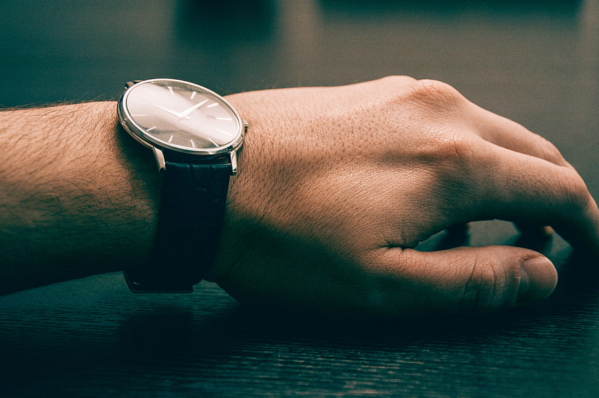 Close-up of a man's wrist wearing a minimalist silver watch