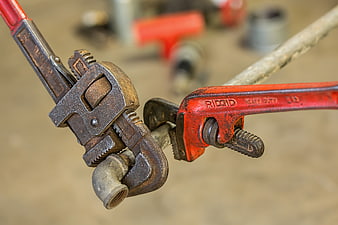 Close-up of rusty pipe wrenches gripping a metal pipe fitting