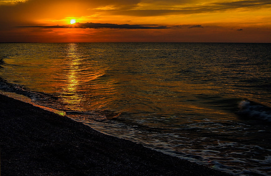 Golden Sunset Over Calm Sea With Pebble Beach