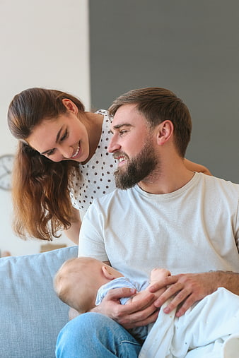 Happy Young Parents Holding Newborn Baby at Home