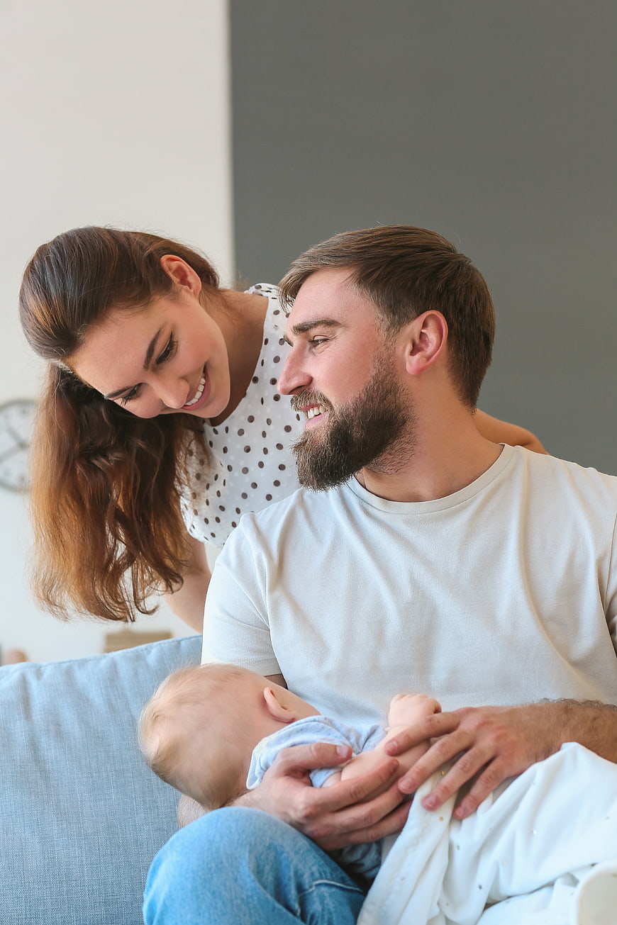 Happy Young Parents Holding Newborn Baby at Home
