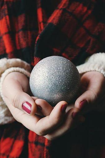 Woman holding silver glitter Christmas ornament in hands