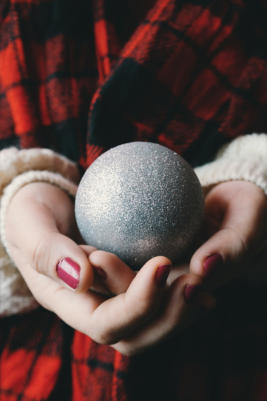 Woman holding silver glitter Christmas ornament in hands