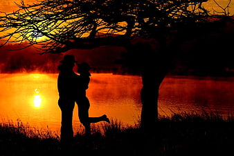 Romantic Silhouette of Lovers Kissing at Sunset by the Water