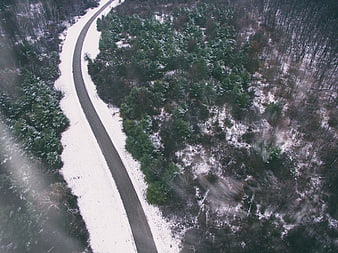 Aerial View of Winding Road Through Snowy Winter Forest