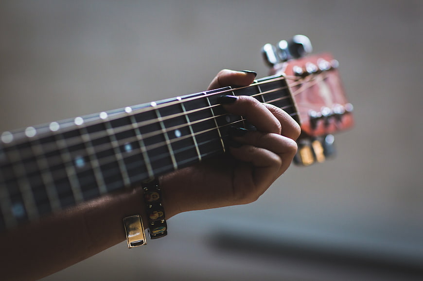 Close-up of woman's hand playing guitar chords